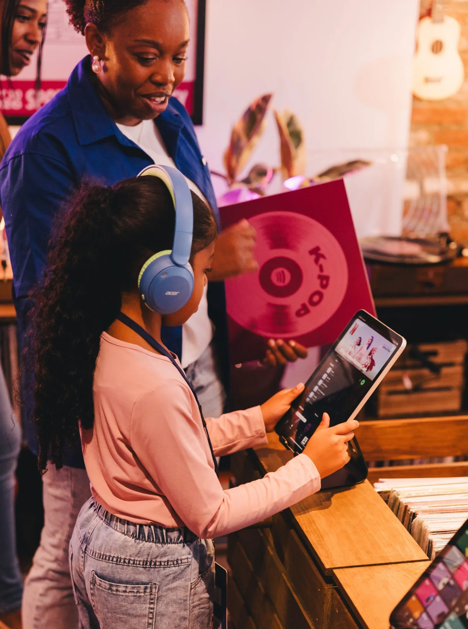 Девочка в наушниках выбирает музыку на планшете на празднике Spotify в Нью-Йорке